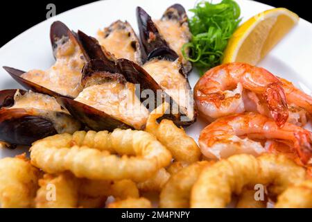 Frutti di mare, cozze, gamberi e calamari in pastella, con limone, primo piano Foto Stock