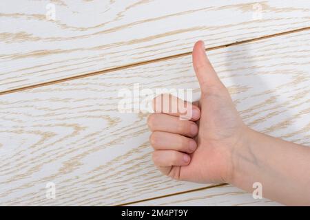 Effettuare a mano un pollice in alto su un sfondo di legno Foto Stock