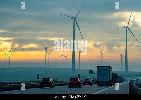 Autostrada A44, nei pressi di Jüchen, che attraversa l'area mineraria di lignite a cielo aperto di Garzweiler, il parco eolico lungo l'autostrada, l'alba, l'NRW, la Germania Foto Stock