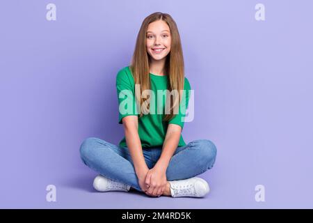 Foto di felice carino signora scolaro seduta godendo tempo libero pausa trascorrere il tempo da solo isolato su sfondo di colore viola Foto Stock