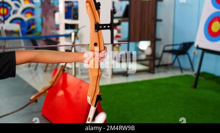 Primo piano delle mani dei bambini che praticano il tiro con l'arco. Tiro con l'arco anello bersaglio. Tiro con l'arco. Esercitarsi con un arco. Concetto ricreativo Foto Stock