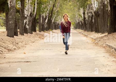 una ragazza corre lungo la strada in un parco autunnale in ucraina, nella città di dnipro Foto Stock