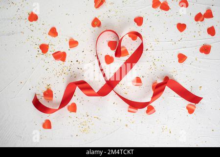 Carta giornaliera di San Valentino. Cuore fatto di nastro e molti cuori di carta su sfondo bianco. Spazio di copia Foto Stock