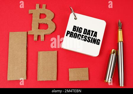 Business e bitcoin concetto. Su una superficie rossa si trovano un simbolo di bitcoin, un grafico, una penna e un blocco note con l'iscrizione - Big data processing Foto Stock
