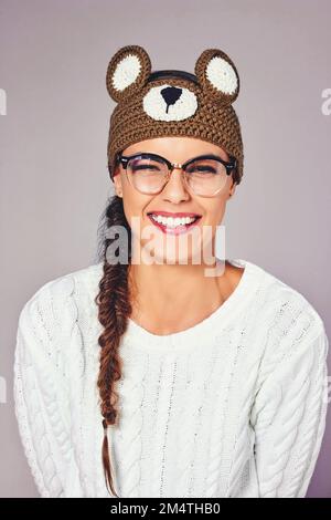 Perché un po 'di senso dell'umorismo va un lungo cammino. Foto studio di una giovane donna che indossa un berretto marrone orsacchiotto. Foto Stock