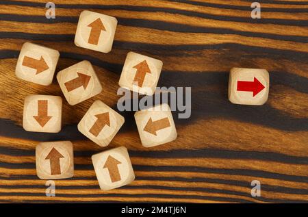 Concetto di leader. Su sfondo marrone, cubi con frecce, un cubo con una freccia rossa a lato. Foto Stock