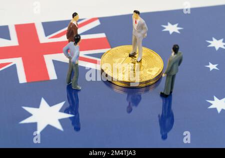 Criptovaluta e concetto di business. Sulla superficie con l'immagine della bandiera dell'Australia sono bitcoins e figurine in miniatura della gente. Foto Stock