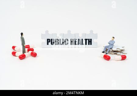 Concetto medico. Sulla superficie bianca della tavoletta, figure umane in miniatura e puzzle con l'iscrizione - LA SALUTE PUBBLICA Foto Stock