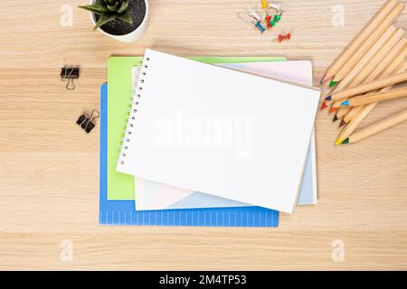 Concetto di ritorno a scuola. Foto dall'alto di blocchi per appunti, penne, affilatrici, righello, pinzatrici, clip, pennarelli ed eraser su tavolo di legno Foto Stock