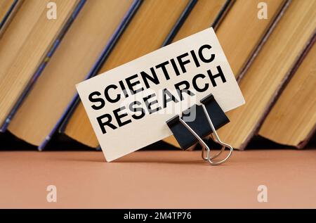 Concetto di educazione e scienza. Sulla tabella sullo sfondo dei libri è un biglietto da visita con l'iscrizione - Ricerca scientifica Foto Stock