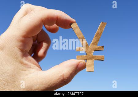 Simboli di valuta. Sullo sfondo del cielo nelle mani di un uomo il simbolo dello yen Foto Stock