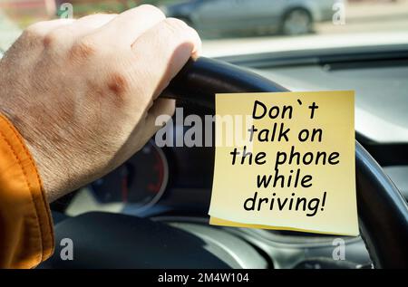 Il concetto di sicurezza dei trasporti. Un uomo tiene il volante, accanto a un adesivo con la scritta - non parlare al telefono durante la guida Foto Stock