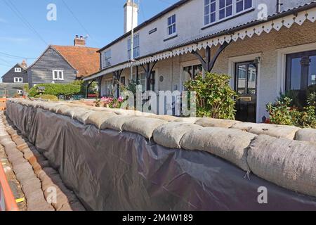 Primo piano di sacchi di sabbia riempiti impilati disposti intorno a cottage fronte mare con allagamento fronte mare ad alte maree sull'isola di Mersea Ovest Essex Inghilterra Regno Unito Foto Stock