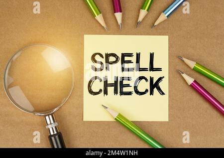 Concetto di istruzione. Sul tavolo sono presenti matite, una lente d'ingrandimento e un adesivo con la scritta "controllo ortografico" Foto Stock