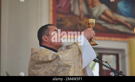 Pervomaysk, Bielorussia - 17 giugno 2022: Un sacerdote cattolico trasforma il vino nel sangue di Gesù. Foto Stock