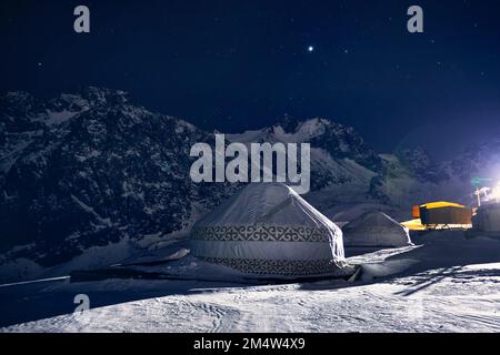 Yurt o yurta casa nomade presso la stazione sciistica di Shymbulak ad Almaty, Kazakhstan. Astrofotografia notturna invernale con stelle contro la vetta della montagna Foto Stock