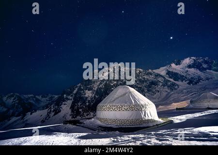 Yurt o yurta casa nomade presso la stazione sciistica di Shymbulak ad Almaty, Kazakhstan. Astrofotografia notturna invernale con stelle contro la vetta della montagna Foto Stock