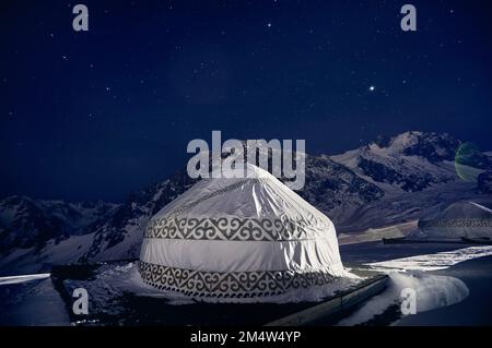 Yurt o yurta casa nomade presso la stazione sciistica di Shymbulak ad Almaty, Kazakhstan. Astrofotografia notturna invernale con stelle contro la vetta della montagna Foto Stock