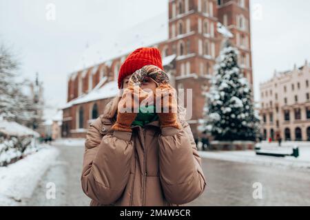 Buon Natale e buone feste. Bella giovane turista femminile in abiti alla moda con pretzel obwarzanek sulla piazza del mercato a Cracovia in Foto Stock