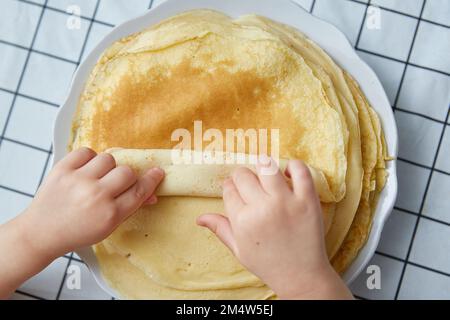 Le mani dei bambini prendono una frittella da una pila. vista dall'alto. Foto Stock