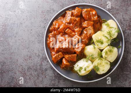 Gulasch di manzo viennese con salsa densa servito con patate bollite primo piano su un piatto sul tavolo. vista orizzontale dall'alto Foto Stock