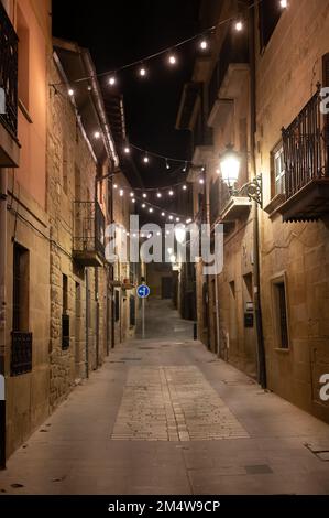 Camminando di notte sulle vecchie stradine medievali del villaggio di Elciego illuminato dalle luci di Natale, Rioja Alavesa, Spagna Foto Stock