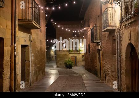 Camminando di notte sulle vecchie stradine medievali del villaggio di Elciego illuminato dalle luci di Natale, Rioja Alavesa, Spagna Foto Stock