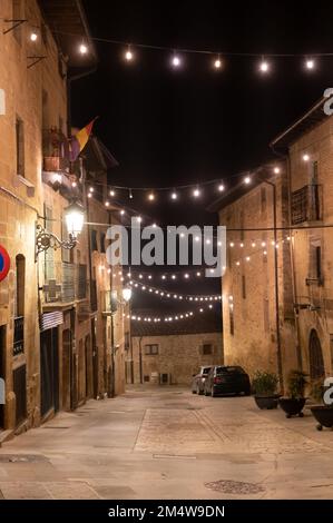 Camminando di notte sulle vecchie stradine medievali del villaggio di Elciego illuminato dalle luci di Natale, Rioja Alavesa, Spagna Foto Stock