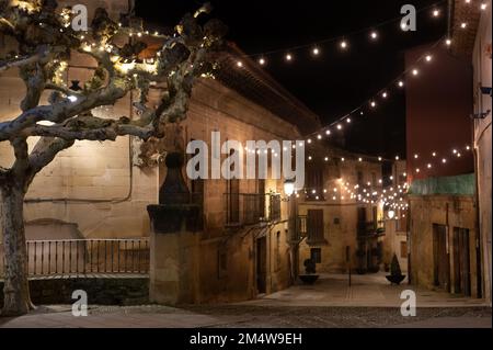 Camminando di notte sulle vecchie stradine medievali del villaggio di Elciego illuminato dalle luci di Natale, Rioja Alavesa, Spagna Foto Stock