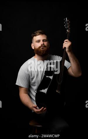 Ritratto di giovane bearded bel chitarrista, artista, compositore, pop rocker star. Concetto musicale. Foto Stock