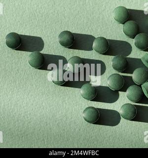 Spirulina compresse integratore nutrizionale mucchio di superficie su sfondo verde . primo piano. vista dall'alto Foto Stock