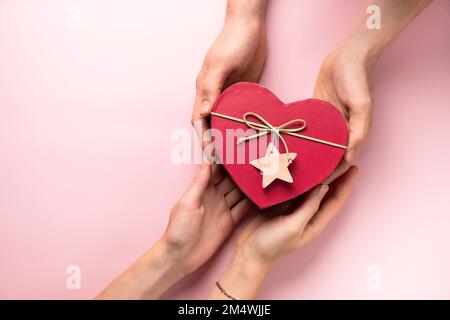 Dando St. Regalo di San Valentino in scatola a forma di cuore in mano. Spazio di copia. Fatto a mano, piatto, vista dall'alto Foto Stock