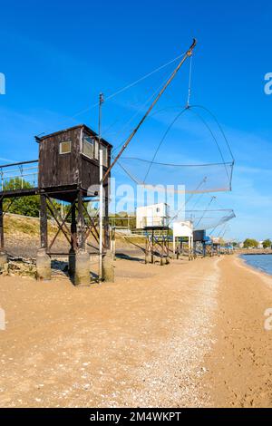 Cabine di pesca con una grande rete di ascensore quadrato chiamato 'carrelet' allineati sulla spiaggia di Saint-Nazaire, Francia, con bassa marea in una giornata di sole estate. Foto Stock