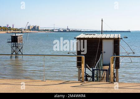 Due cabine di pesca in legno con una grande rete di ascensore quadrata chiamata 'carrelet' stand sulla spiaggia di fronte al ponte di Saint-Nazaire in una giornata di sole estate. Foto Stock