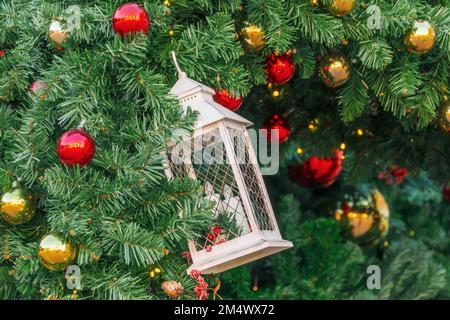 Lanterna e candele come una decorazione di Natale sui rami di un abete rosso, palline rosse, coni e bacche, sfondo di Natale Foto Stock