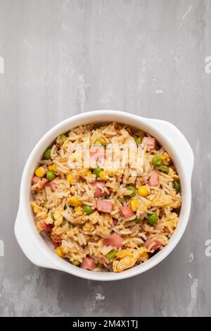 Riso con mais. piselli, prosciutto su ciotola bianca piccola Foto Stock