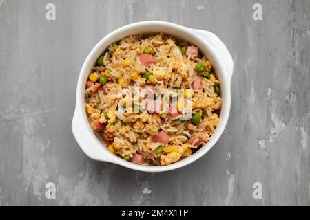 Riso con mais. piselli, prosciutto su ciotola bianca piccola Foto Stock