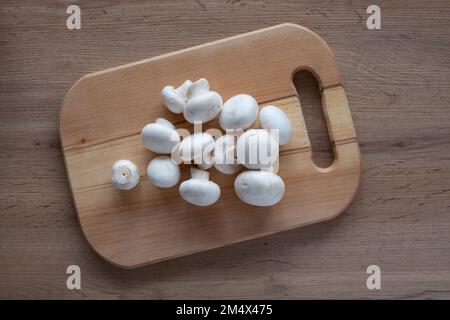Champignons fresco su una tavola di legno sul tavolo. Vista dall'alto di verdure fresche per cucinare. Foto Stock