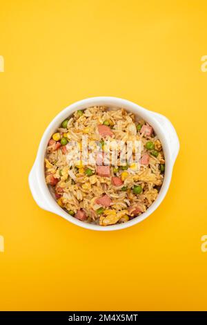 Riso con mais. piselli, prosciutto su ciotola bianca piccola Foto Stock
