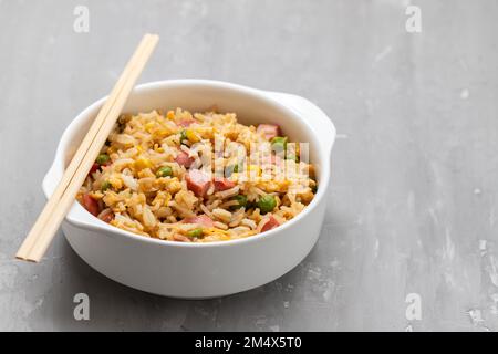 Riso con mais. piselli, prosciutto su ciotola bianca piccola Foto Stock