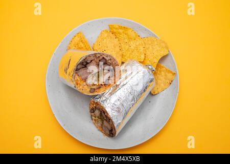 Burrito di manzo messicano su piccolo piatto con patatine nachos sul piatto Foto Stock