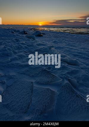 Il ghiaccio bloccato dalla raffica di sole che si affaccia sull'orizzonte è un blu profondo sulla riva dell'isola di Cana del lago Michigan, Door County, Wisconsin Foto Stock