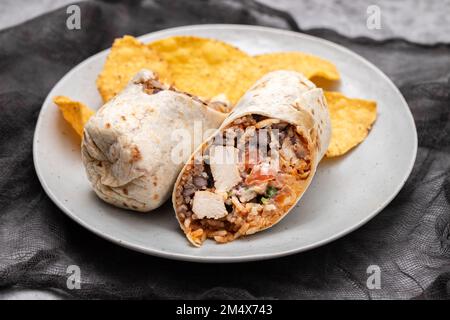 Burrito di manzo messicano su piccolo piatto con patatine nachos sul piatto Foto Stock