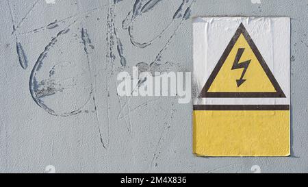 vecchio cartello di pericolo con indicazione di alta tensione sulla porta di un edificio industriale Foto Stock