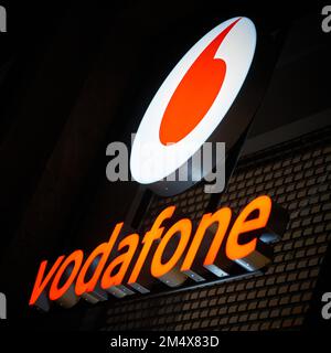 Pubblicità illuminata del fornitore di telefonia mobile Vodafone nel centro di Berlino in serata Foto Stock