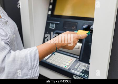 Mano di donna che inserisce la carta di credito in bancomat Foto Stock