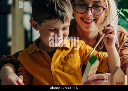 Felice madre e figlio pittura case modello in legno Foto Stock