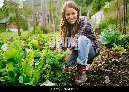 Felice giovane donna che piantano verdure in giardino Foto Stock