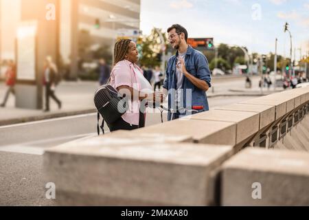 Felice giovane uomo e donna che parlano tra di loro da ringhiera Foto Stock