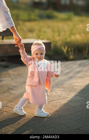 Ragazza cute del bambino che tiene la mano della madre e che cammina sul sentiero Foto Stock
